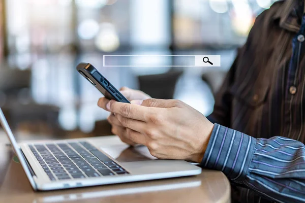 Veri Arama Teknolojisi Arama Motoru optimizasyonu. Akıllı telefonları kullanarak internet sitesinde arama kutucuğu simgesi ve masadaki dizüstü bilgisayarla çalışan insan elleri.