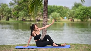 Asyalı zayıf kadın gündüz vakti parkta yoga yapıyor.