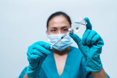Beyaz zemin üzerinde covid-19 virüsünü korumak için şırınga ve aşı kullanan Asyalı doktor