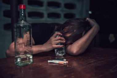 Asyalı kadın gece evde tek başına votka içiyor.