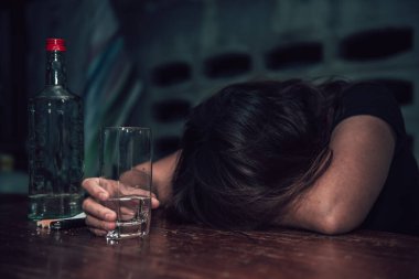 Asyalı kadın gece evde tek başına votka içiyor.