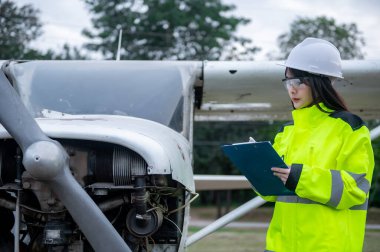 Teknisyen uçağın motorunu tamir ediyor, kadın uzay mühendisi uçak motorlarını kontrol ediyor.