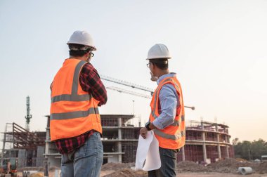 Büyük bir inşaat projesinde çalışan iki Asyalı mühendis.