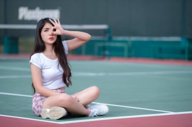 Hipster Asyalı kız fotoğraf çektirmek için poz verir, tenis kortunda güzel bir kadın tasvir eder, modern Taylandlı genç bir kızın yaşam tarzı...