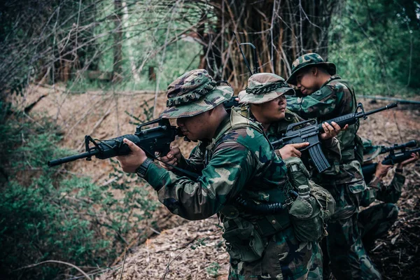 一队拿着机关枪在森林里行进的士兵 身着战斗制服在树林里战斗的士兵 范德巡逻队在热带雨林里倾斜着 — 图库照片