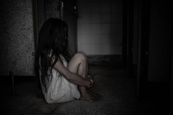 Sad girl sitting on the floor in dark room