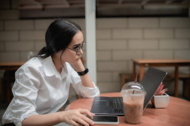 Havalı Asyalı kız, Tayland 'daki bir kahve dükkanında dizüstü bilgisayarla oturmuş dinleniyor.