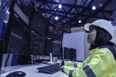 Yüksek performanslı bilgisayar mühendisi. Büyük fabrikada bir sürü monitörü var.