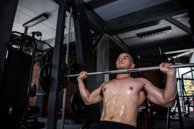 Spor salonunda çalışan yakışıklı bir adam, ağırlık kaldıran Asyalı bir adam spor müsabakası için ağırlık kaldırıyor.