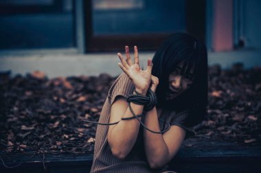 Asyalı rehine kadın. Gece vakti iple bağlanmış.