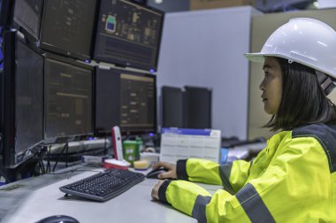 Yüksek performanslı bilgisayar mühendisi. Büyük fabrikada bir sürü monitörü var.