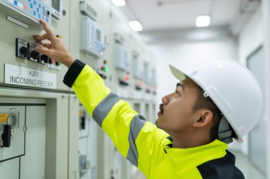 Elektrik mühendisi kontrol odasındaki elektrik dağıtım kabinesinde voltajı kontrol ediyor.
