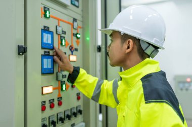 Elektrik mühendisi kontrol odasındaki elektrik dağıtım kabinesinde voltajı kontrol ediyor.
