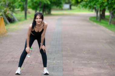 Asyalı zayıf kadın parkta tek başına egzersiz yapıyor, antrenmandan yorgun düşmüş.