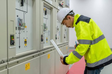 Elektrik mühendisi kontrol odasındaki elektrik dağıtım kabinesinde voltajı kontrol ediyor.