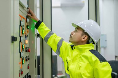 Elektrik mühendisi kontrol odasındaki elektrik dağıtım kabinesinde voltajı kontrol ediyor.