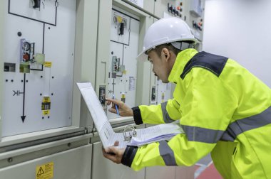 Elektrik mühendisi kontrol odasındaki elektrik dağıtım kabinesinde voltajı kontrol ediyor.
