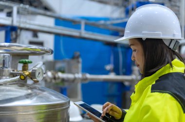 Tayland 'da, ameliyathanede çalışan Asyalı mühendis kask takıyor, özenle ve sabırla çalışıyor, hidrojen tankının valf düzenleyicisini kontrol ediyor..