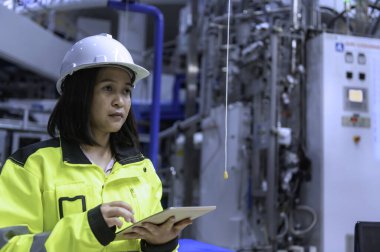 Tayland 'da, ameliyathanede çalışan Asyalı mühendis kask takıyor, özenle ve sabırla çalışıyor, hidrojen tankının valf düzenleyicisini kontrol ediyor..