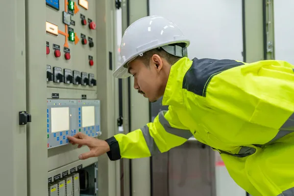 Electrical engineer man checking voltage at the Power Distribution Cabinet in the control room