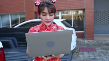 Geleneksel giyimli Asyalı kadın dışarıda dizüstü bilgisayar kullanıyor.