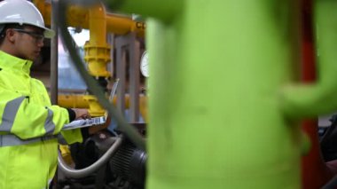 Kazan dairesinde çalışan gözlüklü Asyalı mühendis, ısıtma sistemi ekipmanlarının teknik verilerini kontrol ediyor, Taylandlılar