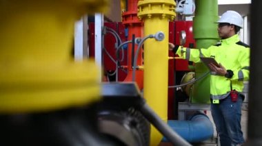 Kazan dairesinde çalışan gözlüklü Asyalı mühendis, ısıtma sistemi ekipmanlarının teknik verilerini kontrol ediyor, Taylandlılar