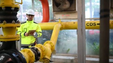 Kazan dairesinde çalışan gözlüklü Asyalı mühendis, ısıtma sistemi ekipmanlarının teknik verilerini kontrol ediyor, Taylandlılar