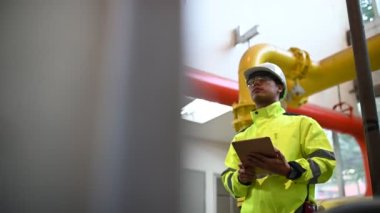 Kazan dairesinde çalışan gözlüklü Asyalı mühendis, ısıtma sistemi ekipmanlarının teknik verilerini kontrol ediyor, Taylandlılar