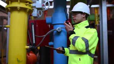 Kazan dairesinde çalışan gözlüklü Asyalı mühendis, ısıtma sistemi ekipmanlarının teknik verilerini kontrol ediyor, Taylandlılar