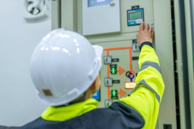 Elektrik mühendisi kontrol odasındaki elektrik dağıtım kabinesinde voltajı kontrol ediyor. Yıllık önleyici bakım, Tayland Elektrikçisi.