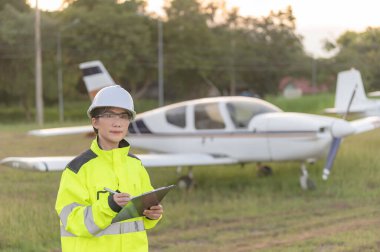 Teknisyen uçağın motorunu tamir ediyor, kadın uzay mühendisliği uçak motorlarını kontrol ediyor, Asyalı tamirci uçak motorlarını kontrol ediyor.