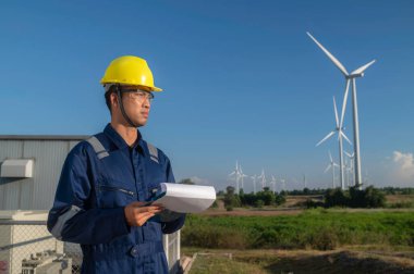 Taylandlı, dağdaki rüzgar türbini çiftliği güç jeneratörü istasyonunda çalışan ve raporu tutan Asyalı mühendisler, iş yerindeki teknisyen