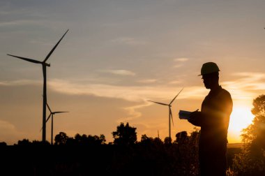 Taylandlı, dağdaki rüzgar türbini çiftliği güç jeneratörü istasyonunda çalışan ve raporu tutan Asyalı mühendisler, iş yerindeki teknisyen