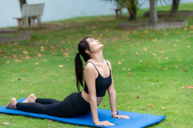 Asyalı zayıf kadın parkta tek başına egzersiz yapıyor, çalışmaktan yoruluyor, yoga konsepti oynuyor.