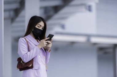 Parktaki güzel Asyalı iş kadınının portresi Covid-19 'u korumak için maske tak.