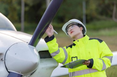 Teknisyen uçağın motorunu tamir ediyor, kadın uzay mühendisliği uçak motorlarını kontrol ediyor, Asyalı tamirci uçak motorlarını kontrol ediyor.