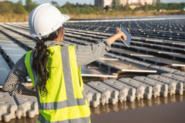 Asian engineer working at Floating solar farm,Renewable energy,Technician and investor solar panels checking the panels at solar energy installation clipart