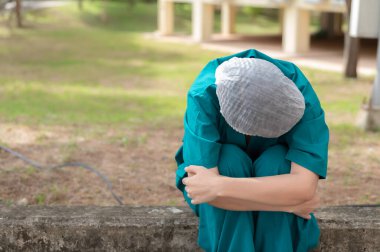 Depresyonda olan Asyalı kadın hemşire yüz maskesi giyiyor mavi üniforma hastane zemininde oturuyor, genç doktor yoğun çalışmanın stresi altında, uluslararası hemşireler günü