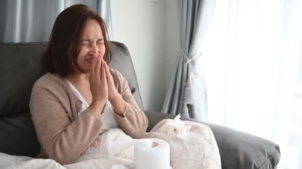 亚洲生病的女人坐在沙发上呆在家里 感觉很糟糕 想躺下休息 在家里用隔离的方法治疗Covid — 图库视频影像
