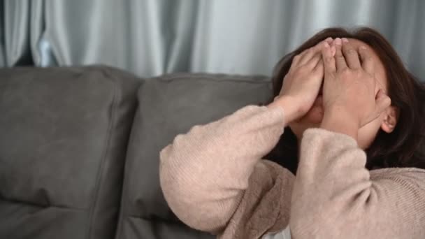 亚洲生病的女人坐在沙发上呆在家里 感觉很糟糕 想躺下休息 在家里用隔离的方法治疗Covid — 图库视频影像