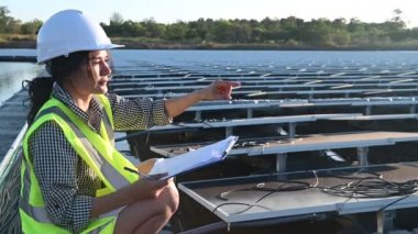 Yüzen güneş çiftliğinde çalışan Asyalı mühendis, yenilenebilir enerji, teknisyen ve yatırımcı güneş panelleri güneş enerjisi kurulumundaki panelleri kontrol ediyor