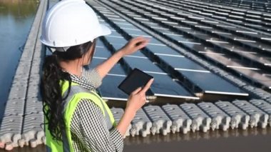 Yüzen güneş çiftliğinde çalışan Asyalı mühendis, yenilenebilir enerji, teknisyen ve yatırımcı güneş panelleri güneş enerjisi kurulumundaki panelleri kontrol ediyor