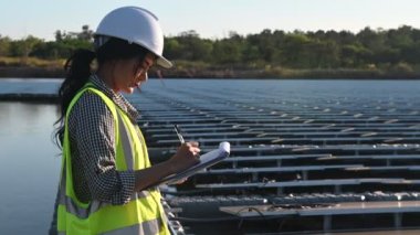 Yüzen güneş çiftliğinde çalışan Asyalı mühendis, yenilenebilir enerji, teknisyen ve yatırımcı güneş panelleri güneş enerjisi kurulumundaki panelleri kontrol ediyor