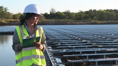 Yüzen güneş çiftliğinde çalışan Asyalı mühendis, yenilenebilir enerji, teknisyen ve yatırımcı güneş panelleri güneş enerjisi kurulumundaki panelleri kontrol ediyor