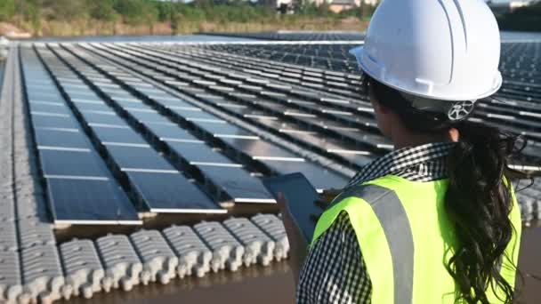 フローティングソーラーファームで働くアジアのエンジニア 再生可能エネルギー 技術者および投資家太陽光パネル太陽エネルギーの設置時にパネルをチェック — ストック動画