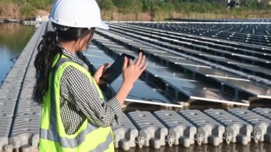Yüzen güneş çiftliğinde çalışan Asyalı mühendis, yenilenebilir enerji, teknisyen ve yatırımcı güneş panelleri güneş enerjisi kurulumundaki panelleri kontrol ediyor