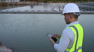 Yüzen güneş çiftliğinde çalışan Asyalı mühendis, yenilenebilir enerji, teknisyen ve yatırımcı güneş panelleri güneş enerjisi kurulumundaki panelleri kontrol ediyor