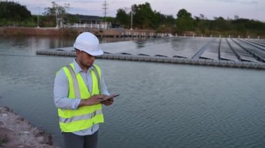 Yüzen güneş çiftliğinde çalışan Asyalı mühendis, yenilenebilir enerji, teknisyen ve yatırımcı güneş panelleri güneş enerjisi kurulumundaki panelleri kontrol ediyor