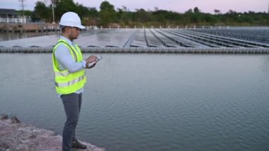 Yüzen güneş çiftliğinde çalışan Asyalı mühendis, yenilenebilir enerji, teknisyen ve yatırımcı güneş panelleri güneş enerjisi kurulumundaki panelleri kontrol ediyor